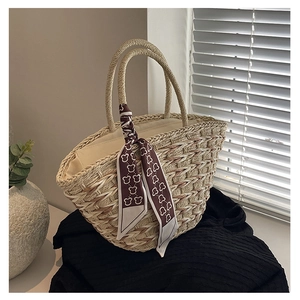 Detail of woven straw handbag featuring natural texture and decorative bear scarf handle
