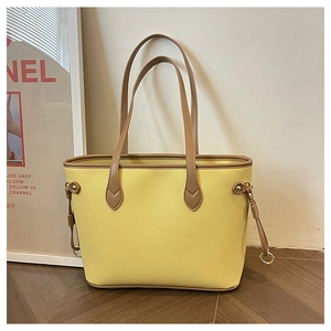 Detail of yellow lychee textured tote bag with brown contrast trim and gold ring drawstring