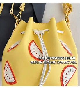 Detail of yellow bucket bag with watermelon patch, drawstring closure and golden hooks
