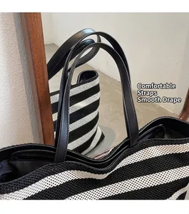Detail of striped knit tote bag featuring premium leather straps and secure zipper closure