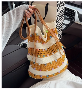 Gros plan du sac cabas tricoté rayé jaune et blanc avec des perles colorées