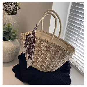 Detailed view of bicolor woven straw tote bag featuring a cute bear pattern silk scarf accessory