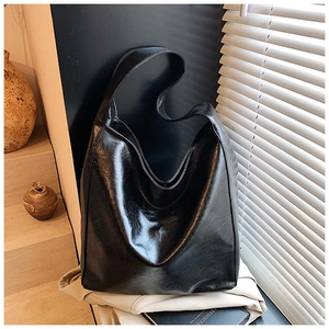 Detailed view of black glossy leather tote bag with elegant light and shadow on the surface