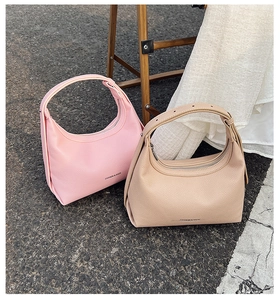 Detailed view of pink and beige lychee textured leather dumpling hobo bags on asphalt