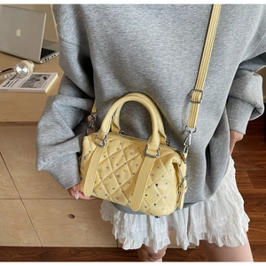 Detail of quilted pale yellow bucket bag with sparkling crystals and twin top handles