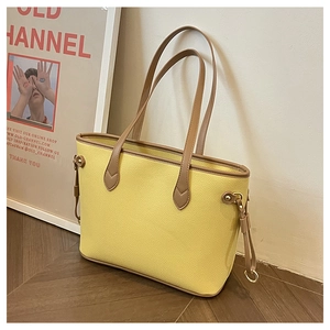 Detail of yellow pebbled leather tote bag with brown straps and drawstring on wood floor