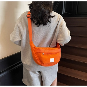 Détail du sac bandoulière croissant orange vif en nylon résistant avec sangle large