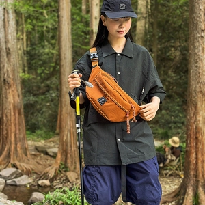 Detail of orange nylon chest bag featuring grid texture and adjustable black strap