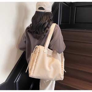 Dettaglio della borsa tote in tela con coulisse laterale regolabile e patch logo in pelle