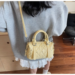 Macro detail of quilted yellow bucket bag with silver studs and smooth leather texture