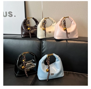 Dettaglio di borse mini in pelle cerata di vari colori con ciondoli a sfera d'oro