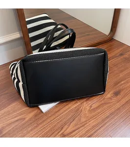Detail of woven beach tote showing the reinforced leather base and black white stripes