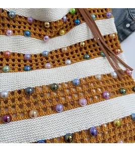 Détail d'un sac cabas en maille rayée avec perles colorées et cordon en cuir