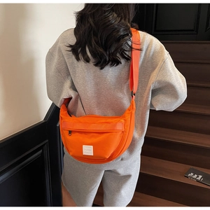 Vue arrière d'un sac bandoulière croissant en nylon orange vif porté par un mannequin