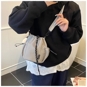 Detail view of a gray canvas drawstring bucket bag featuring side mesh pocket and wide strap