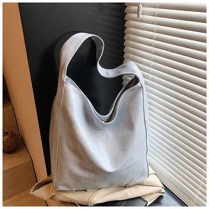 Detail of light blue large capacity tote bag featuring wide shoulder straps and matte leather