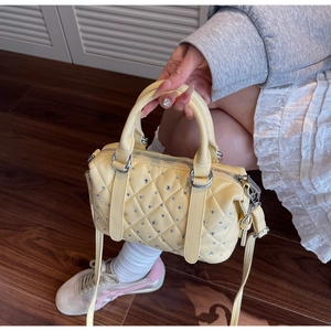 Detail of light yellow quilted bucket bag with sparkly rhinestone studs and silver zipper