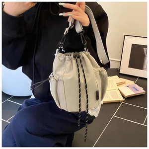 Close-up of light gray canvas bucket bag with drawstring closure and mesh pockets