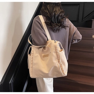 Dettaglio della borsa tote in tela beige con coulisse laterale e tracolla regolabile