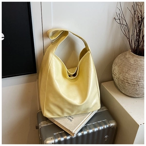 Detail of light yellow tote bag with magnetic closure on silver suitcase background