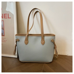 Detail of light blue lychee pattern tote bag with brown trim and metal ring hardware