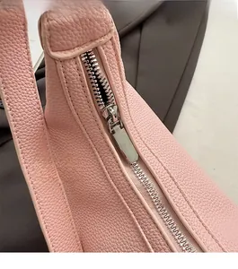 Close-up of pink lychee leather dumpling bag with smooth silver metal zipper detail