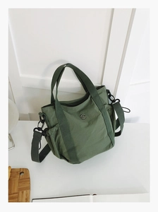 Detail of army green nylon handbag with adjustable strap and metallic M logo emblem