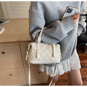 Detailed view of beige quilted handbag with sparkling rhinestone studs and silver hardware