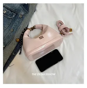 Dettaglio borsa a luna in pelle verniciata rosa con chiusura dorata e tracolla