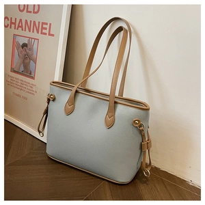 Detail of light blue lychee pattern leather tote bag with brown contrast straps