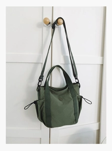 Detail of olive green nylon bag with drawstring closure and circular metal logo