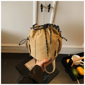 Detail of light khaki drawstring bucket bag with mesh pocket and casual sports strap