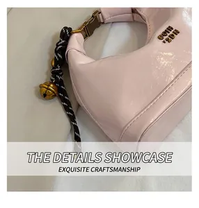 Dettaglio della borsa a mezzaluna in pelle cerata rosa con logo oro e pendente