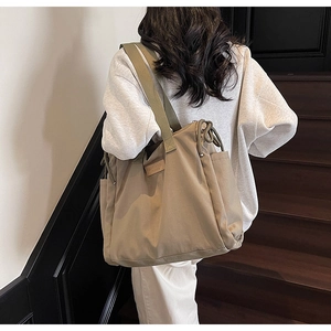 Vista dettagliata di una borsa tote in tela kaki con coulisse e tracolla larga su modella