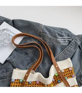 Détail de la bandoulière en cuir marron et des perles colorées sur le sac cabas tissé