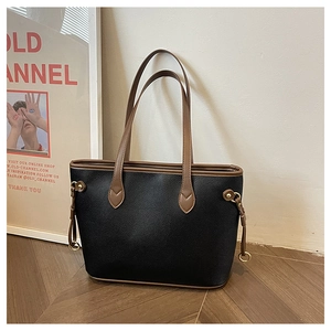 Detail of black lychee grain leather tote bag with brown contrast straps and metal rings