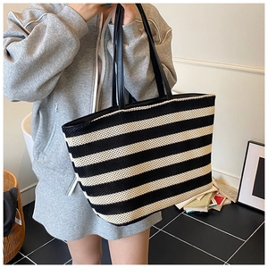 Détail d'un grand sac cabas tissé à rayures noires et blanches avec anses en cuir