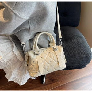 Detail of cream white quilted bucket bag with rhinestones shown on a model's shoulder