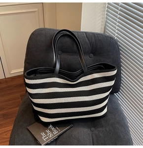 Detail of black and white striped knit tote bag texture and faux leather strap on a chair