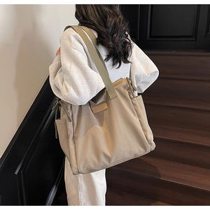 Dettaglio della capiente borsa tote in tela kaki con coulisse laterali e toppa con logo