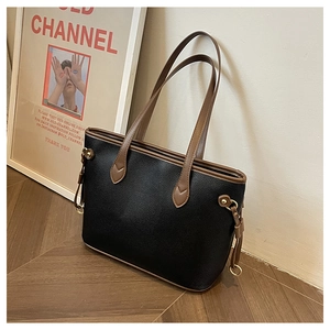 Close-up of black litchi grain leather tote bag with brown handles and gold buckle detail