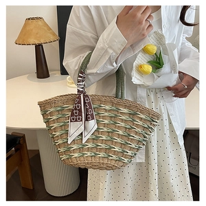 Detail of woven straw handbag with green handle and decorative teddy bear scarf