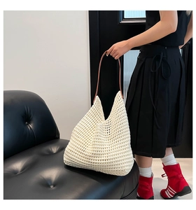 Detailed close-up of a hollow woven tote bag in creamy white with slim brown leather straps