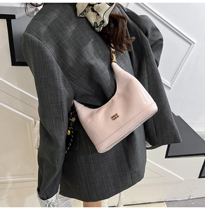 Dettaglio della borsa hobo in pelle verniciata rosa chiaro con finitura lucida e logo in metallo