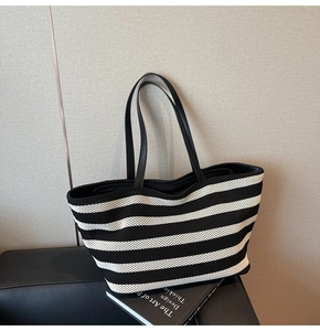Detail of black and white striped woven tote bag with premium leather shoulder straps