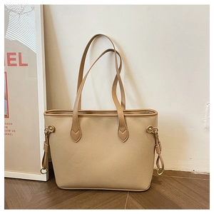 Detailed close-up of beige textured leather tote bag on wooden floor with sunlight