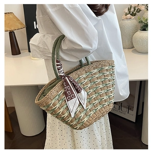 Close-up of woven handbag in natural beige and green with a decorative silk scarf