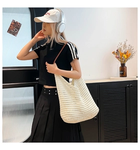 Detail of white hollow woven tote bag with brown leather shoulder straps and knit texture