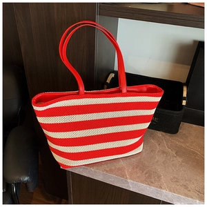 Détail du sac cabas tissé à rayures rouges et blanches avec poignées sur une table