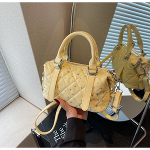 Detail of yellow quilted leather bag with sparkling rhinestones and silver hardware